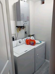 full sized laundry room with instant gas water heater