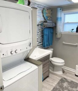 Main bathroom with full-sized tub-shower, vanity, and stacked washer & dryer