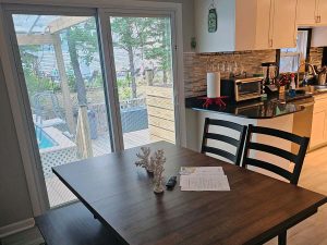 Dining room with electric fireplace, large LED TV, whole house sound, poolside views, and open to kitchen