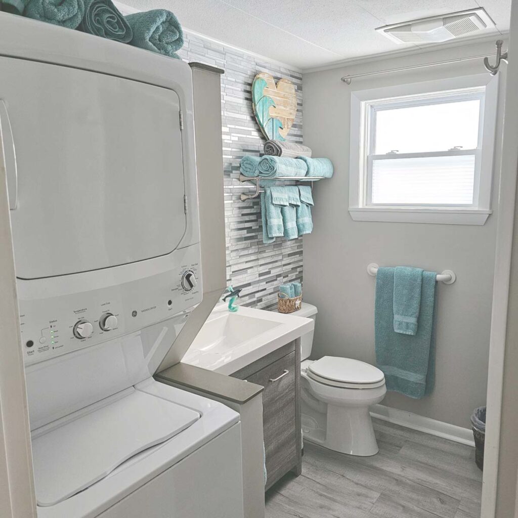 Main bathroom with full-sized tub/shower, toilet, vanity, and stacked washer & dryer