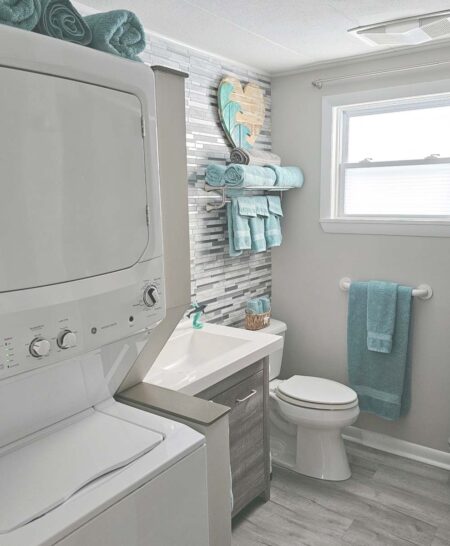 Main bathroom with full-sized tub/shower, toilet, vanity, and stacked washer & dryer