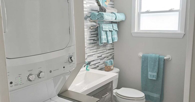 Main bathroom with full-sized tub/shower, toilet, vanity, and stacked washer & dryer