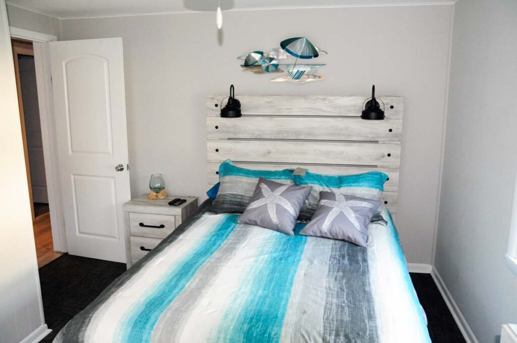 Bedroom 1 with queen sized adjustable bed, large LED TV, and slider to covered outdoor sitting area and walkaround deck to back